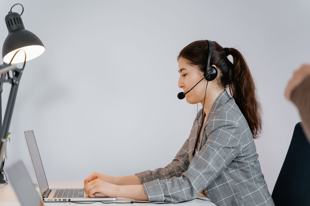 Nhân viên sales đeo headset làm việc bên laptop