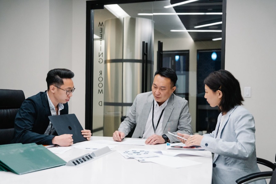 Ba đồng nghiệp cùng xem báo cáo trong phòng họp